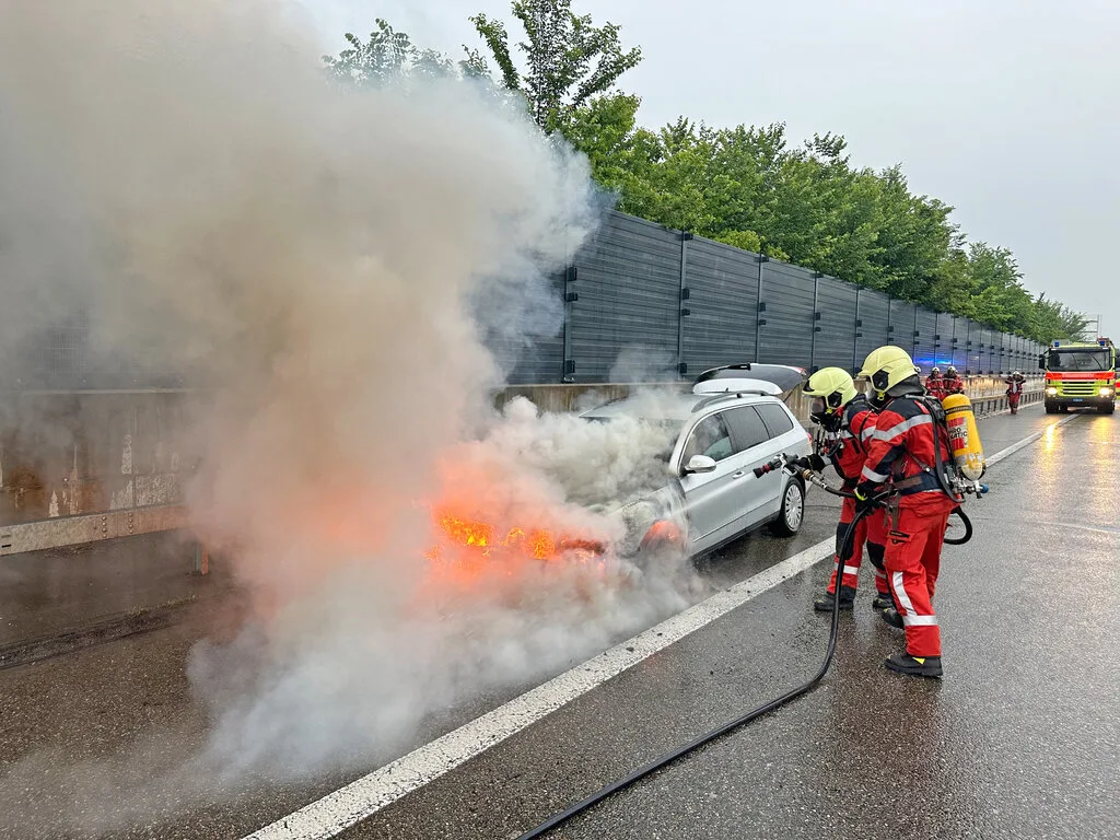 Erfolgreicher Löschangriff: die Stützpunktfeuerwehr Uster im Einsatz. Ein brennendes Auto und löschende Feuerwehrleute, dazu starke Rauchentwicklung.